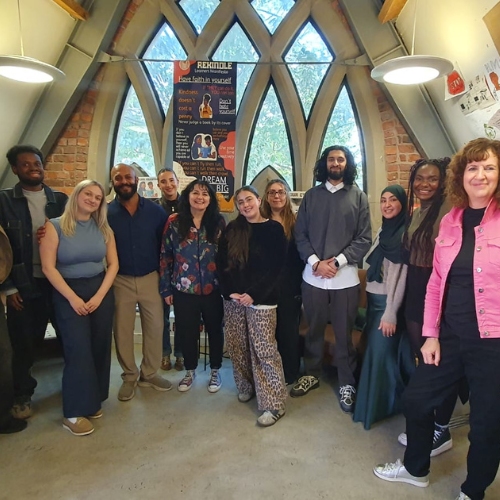A group of young people in a room smile at the camera